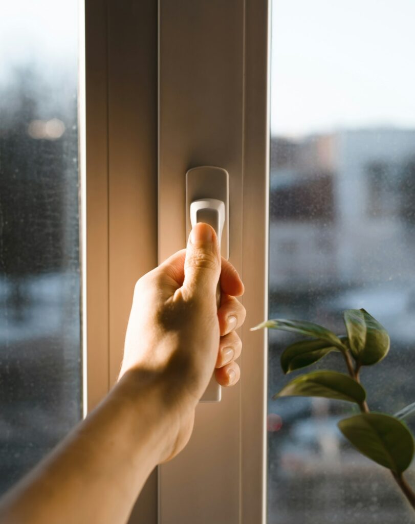 Male hand holding the handle of the window. Man opening (closing) a window. Sun glare on the hand